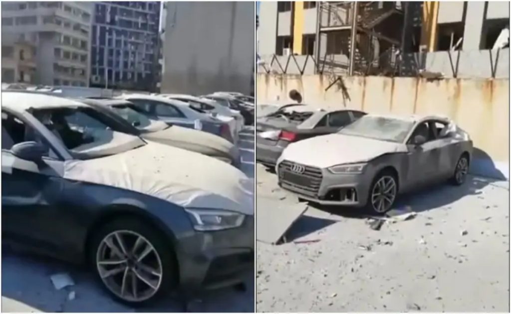 Cette image montre un parking d'un concessionnaire dans la ville avec des véhicules Audi endommagés qui étaient prêts à être livrés aux clients.