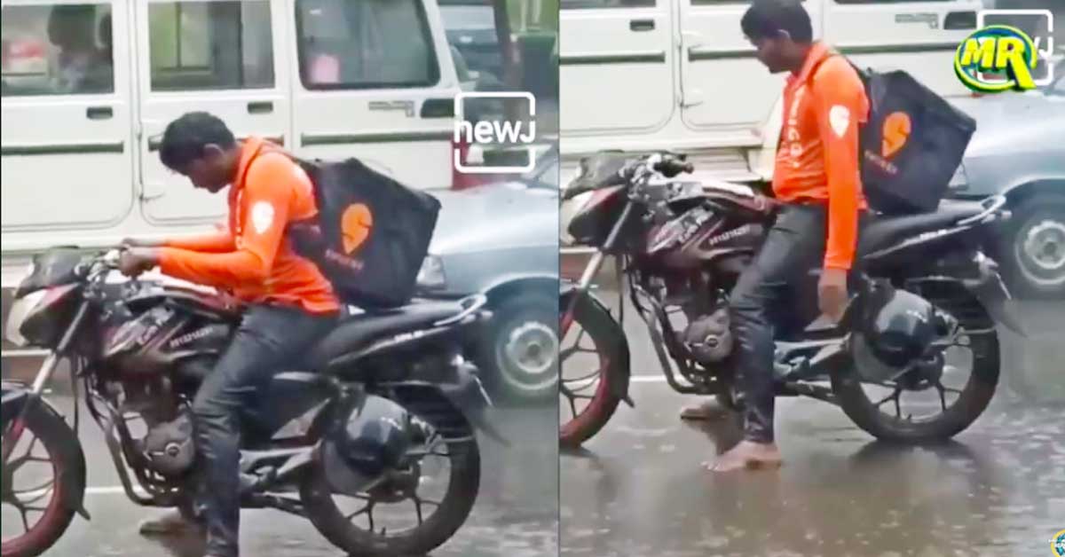 Swiggy delivery boy waiting at a traffic signal in heavy rain