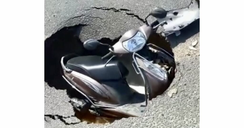 Scooty Stuck in hole on the road