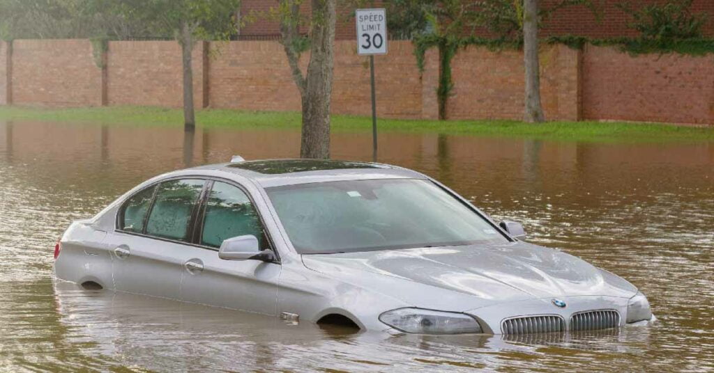 A BMW 5 Series stuck on a waterlogged street.